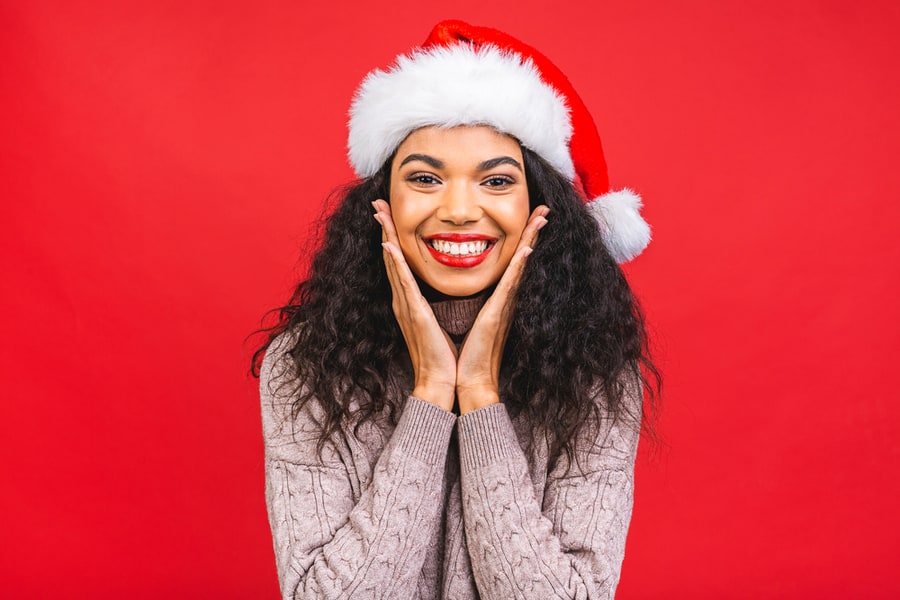 Portrait Of Beautiful African American Female Woman Model Wearing Santa Hat Isolated Over Red Background.