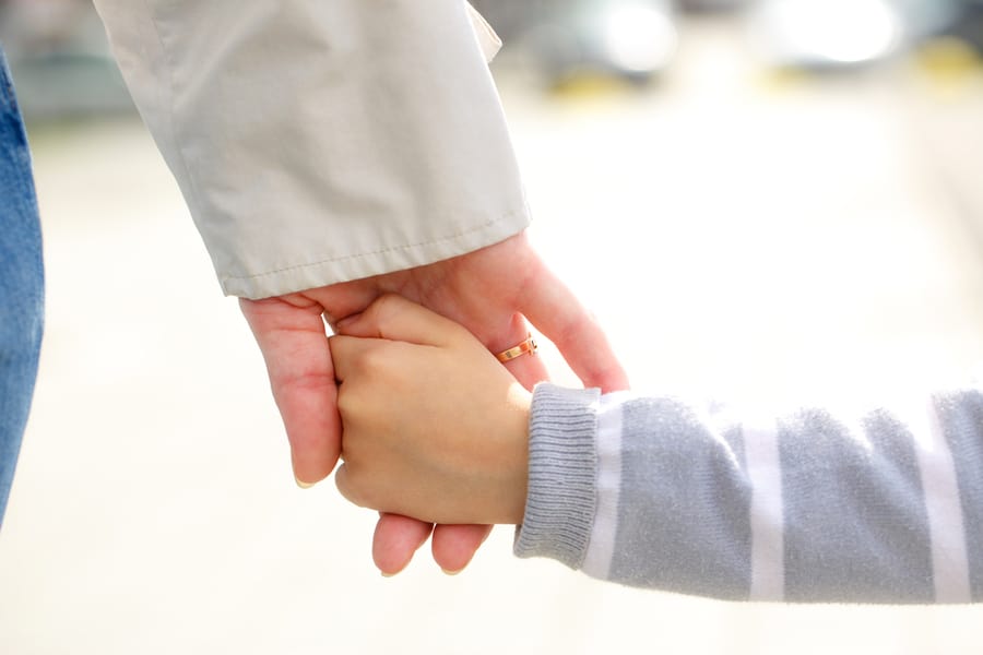 Mother And Child Holding Hands Outdoors In Closeup