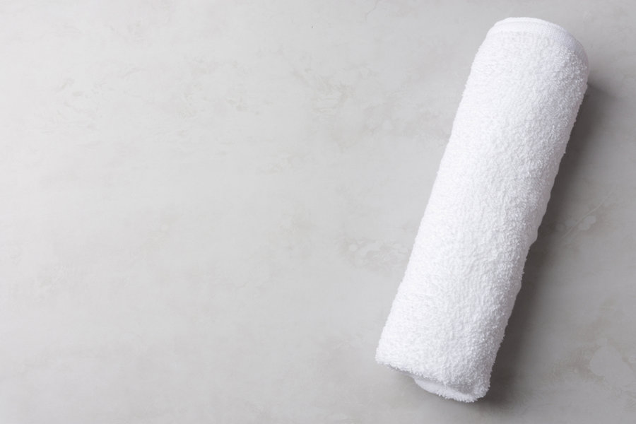 Rolled Clean White Fluffy Terry Towel On Pastel Gray Stone Background.