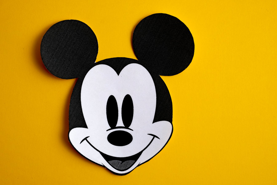 Black And White Face Of Mickey Mouse Out Of Paper On A Yellow Background.