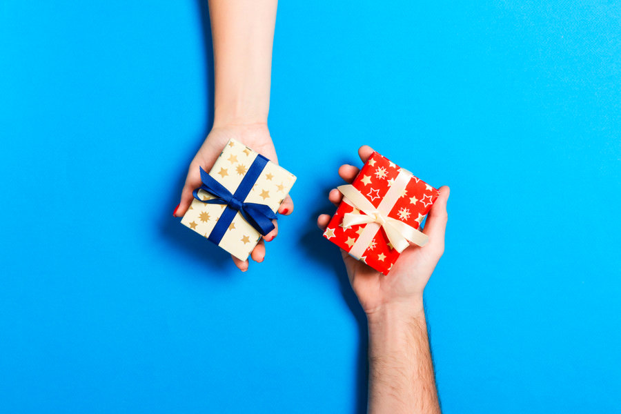 Top View Of A Woman And A Man Exchanging Gifts On Colorful Background.