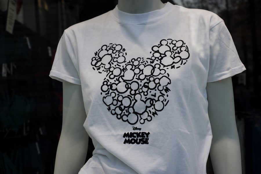 Closeup Of White Printed Tee-Shirt With Mickey Mouse Symbols In A Fashion Store Showroom