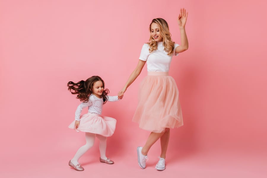 Full-Length Shot Of Cheerful Adult Lady And Little Girl In Light Dresses Dancing On Isolated Background