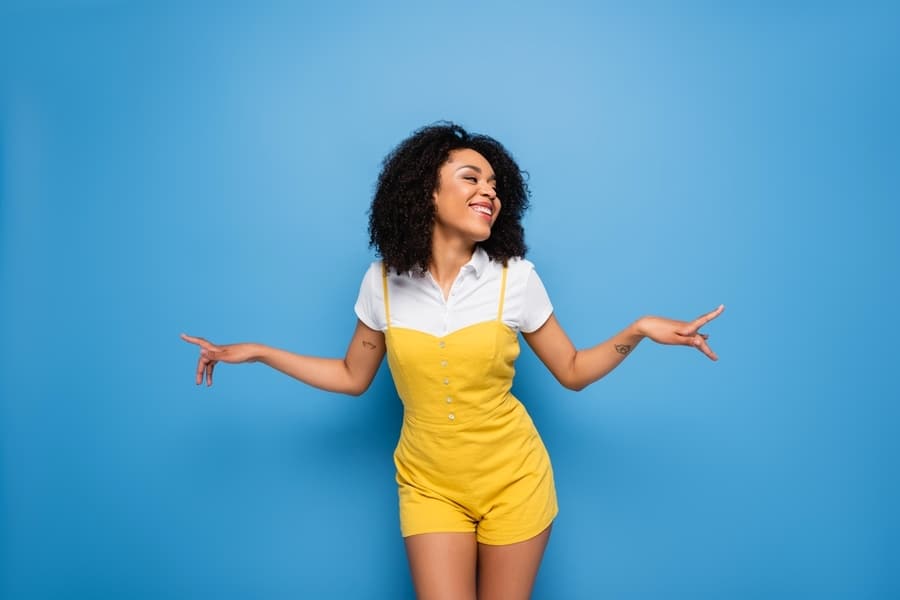 Happy African American Woman In Yellow Jumpsuit Pointing With Fingers