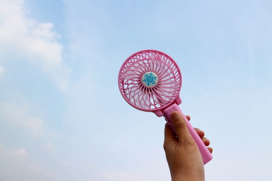 Mini Pink Portable Fan With Hand Holding Handle Mini Fan Shows In Light Blue Clouds Sky Background