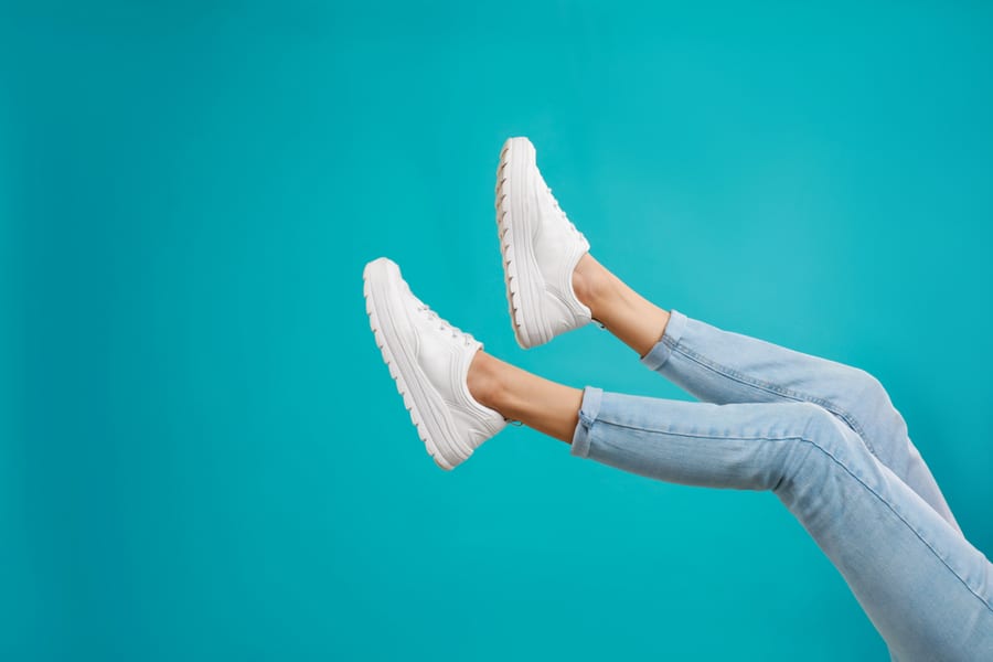 Woman In Stylish Sport Shoes On Light Blue Background