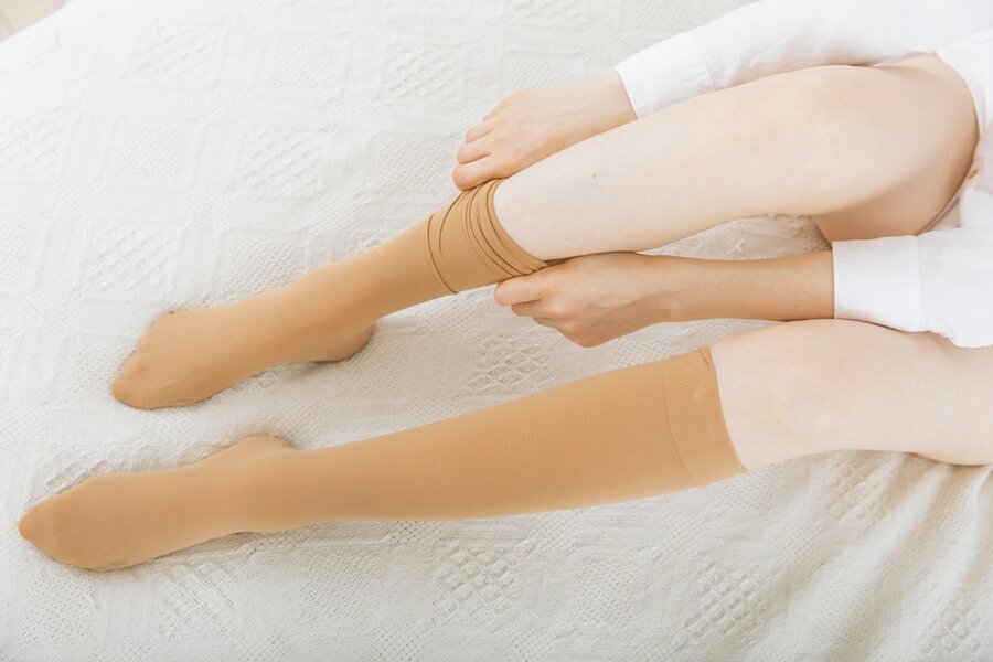 Beige Compression Stockings On A Woman In A White Room