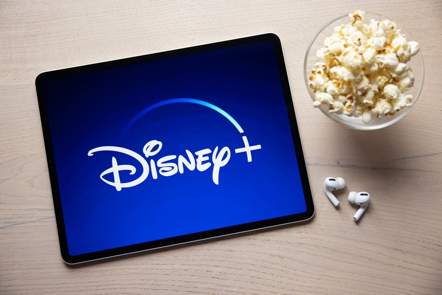 Disney+ Logo On Ipad With Popcorn And Wireless Earbuds