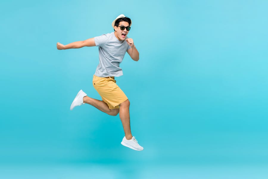 Energetic Happy Young Asian Man Jumping Studio Shot