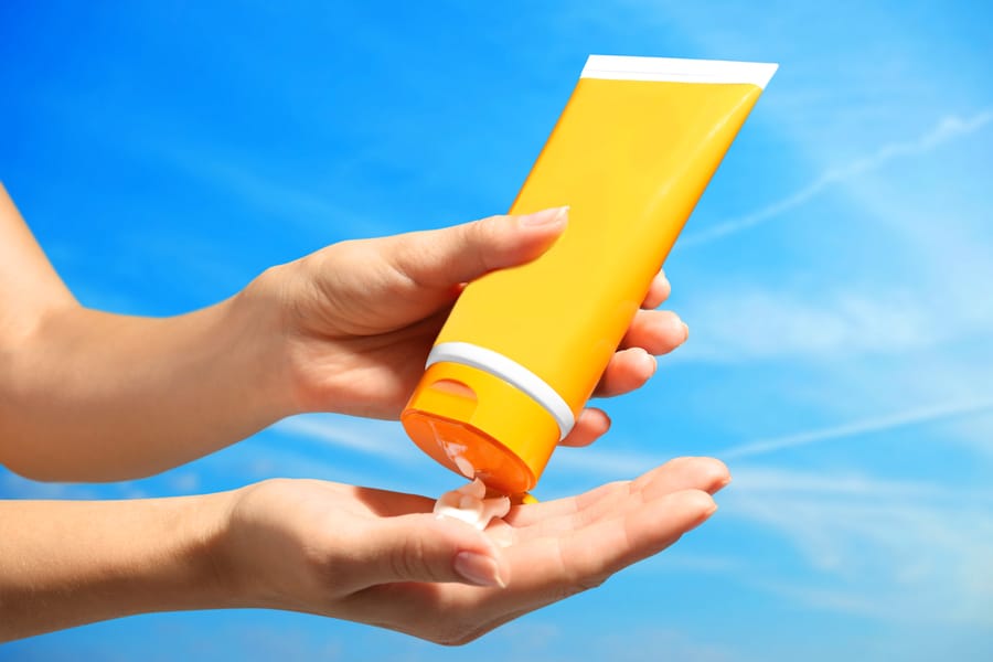 Female Hands With Sun Protection Cream On Sky Background