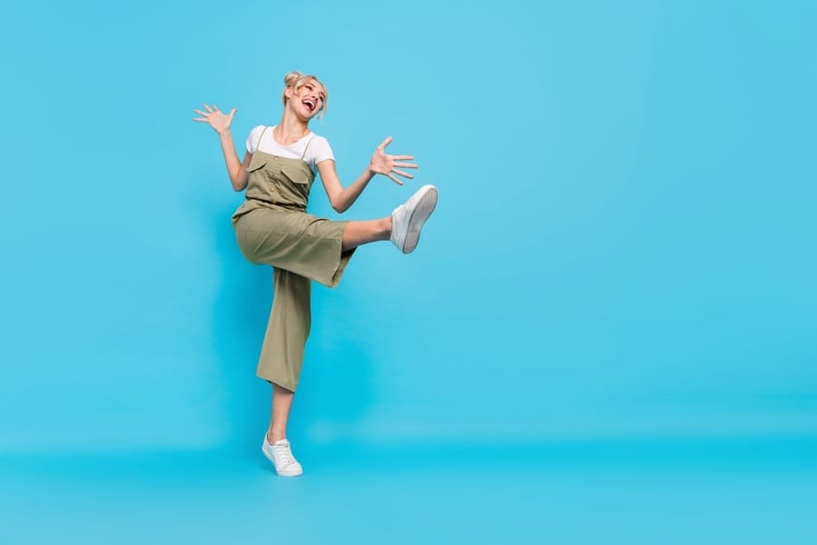 Full Length Photo Of Cool Blond Lady Dance Look Promo Wear T-Shirt Overall Shoes Isolated On Blue Background