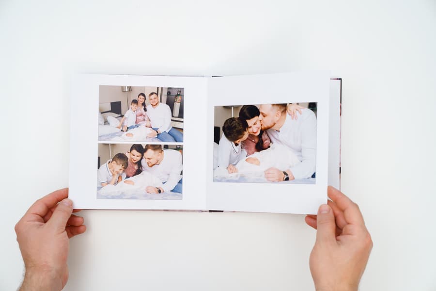 Hands Flip Through A Photobook From A Home Family Photo Shoot With A Newborn Child