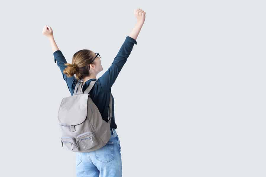 Happy Lady Wearing A Backpack With Arms Raised On Air