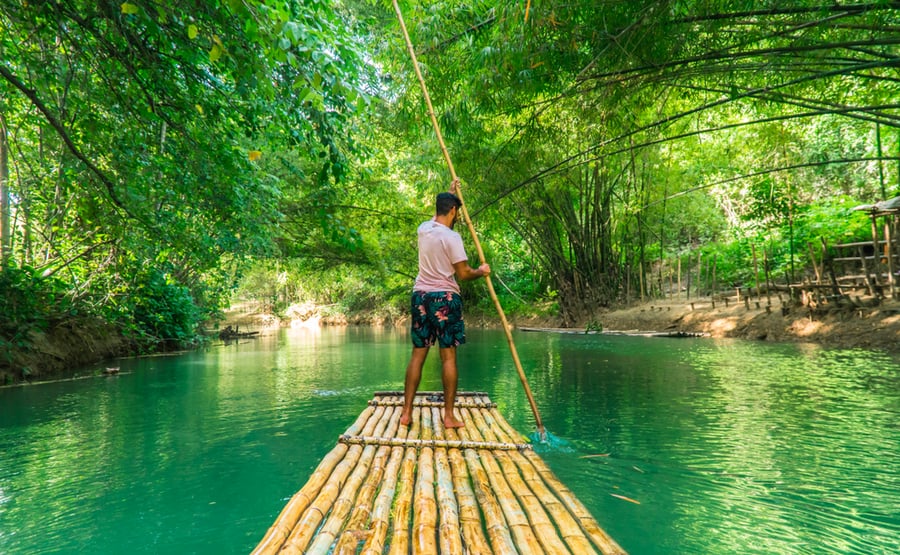 Landscape Shot Of Man (Tourist) Rowing Bamboo Raft, Whilst On Cruise On Vacation