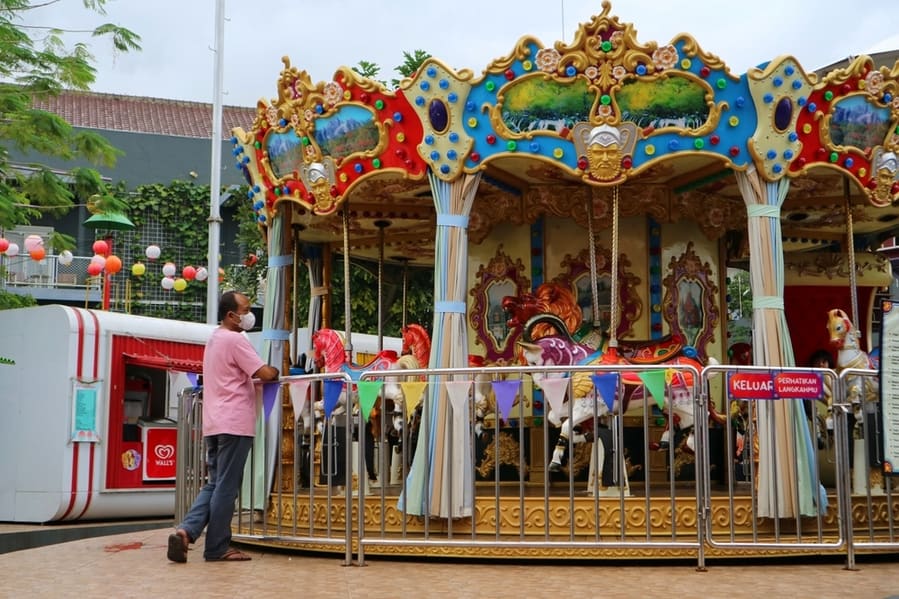 Parent Waiting For Children Riding Colorfull Carousel In The Park