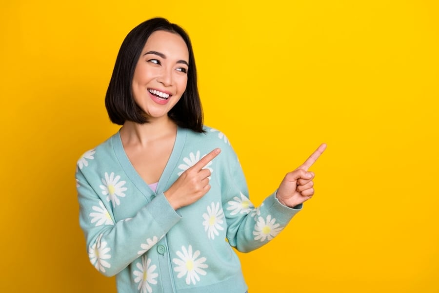 Photo Of Adorable Cheerful Glad Lady Wear Stylish Spring Outfit Look Empty Space Presenting Novelty Isolated On Yellow Color Background