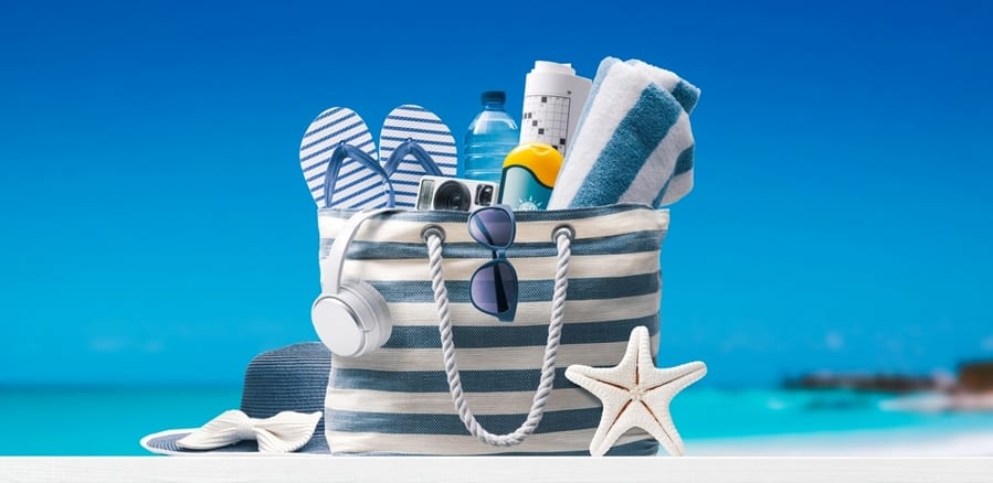 Stylish Beach Bag With Accessories And Tropical Beach In The Background