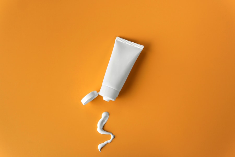 Top View Blank Label Facial Skincare White Tube Bottle With Lid Open Product Squeezed Lotion Or Cream Texture On Plain Solid Orange Background