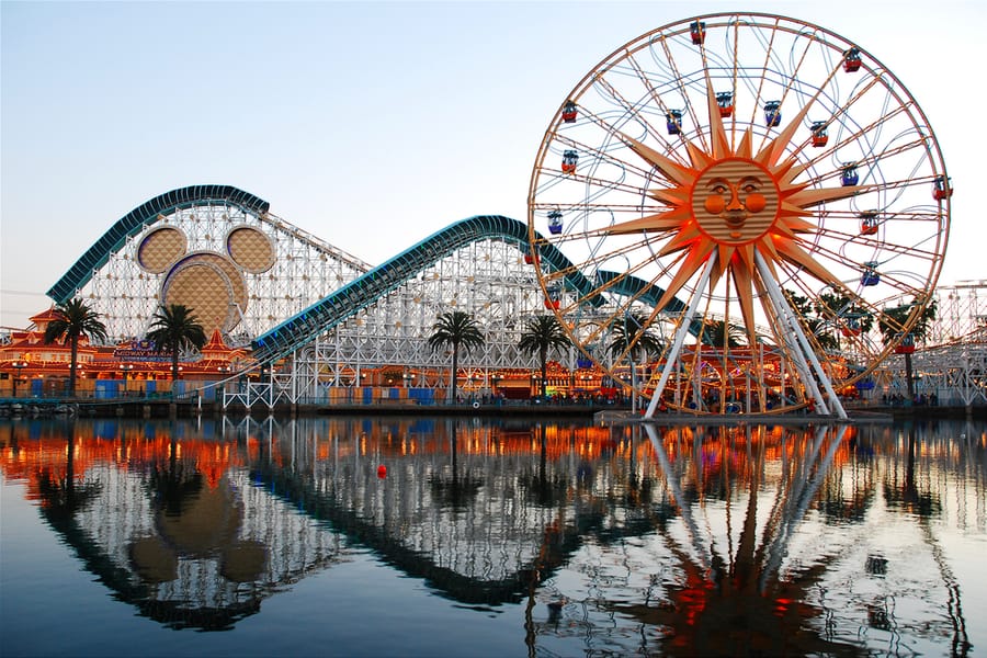 Wheel, Roller Coaster And Rides Of Paradise Pier In Anaheim California Are Reflected In The Lake