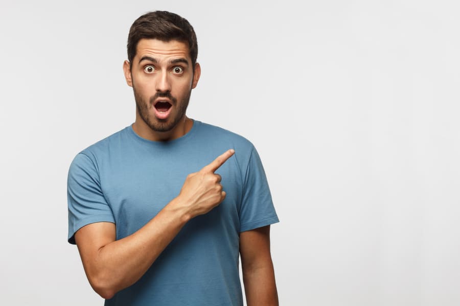 Young Surprised Man In Blue T-Shirt Pointing Right With His Finger